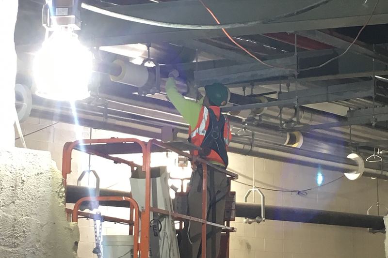 Installing insulation around overhead HVAC ductwork in the future LIRR passenger concourse. (CM014B, 11-27-2018)